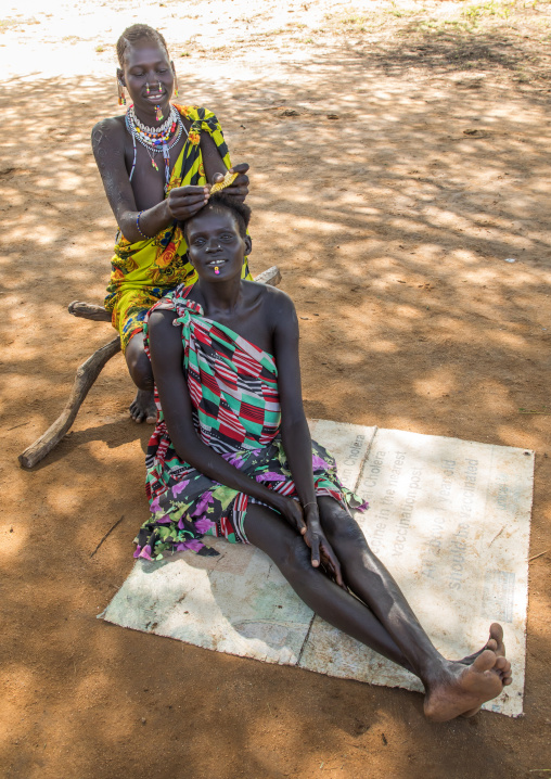 Larim tribe woman making braids to a friend, Boya Mountains, Imatong, South Sudan