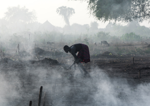 Mundari tribe woman taking care of a bonfire made with dried cow dungs to repel mosquitoes, Central Equatoria, Terekeka, South Sudan