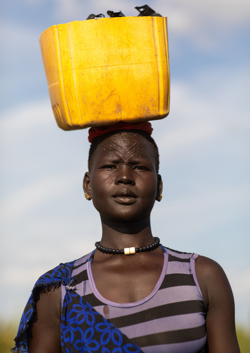 Portrait of a Mundari tribe woman with scarifications on the forehead carrying a jerrican, Central Equatoria, Terekeka, South Sudan