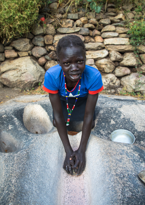 Lotuko tribe woman grinding grains in a hole in the rock, Central Equatoria, Illeu, South Sudan