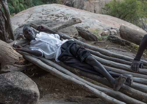 Lotuko tribe man resting on a wood bed, Central Equatoria, Illeu, South Sudan