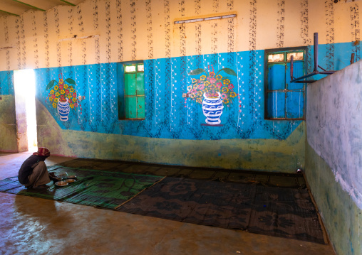 Sudanese man eating on the floor in a restaurant with decorated walls, Khartoum State, Khartoum, Sudan