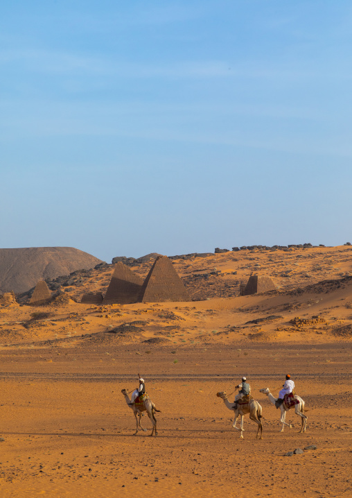 Sudanese men and their camels in front of the pyramids of the kushite rulers at Meroe, Northern State, Meroe, Sudan