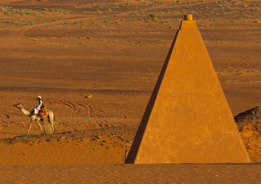 Sudanese man and his camel in front of the pyramids of the kushite rulers at Meroe, Northern State, Meroe, Sudan