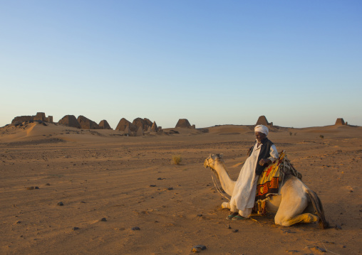 Sudan, Kush, Meroe, man and his camel in front of the pyramids and tombs in royal cemetery