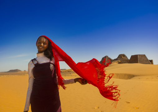 Sudan, Kush, Meroe, young sudanese woman in front of the pyramids and tombs in royal cemetery