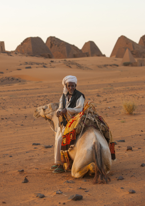 Sudan, Kush, Meroe, man and his camel in front of the pyramids and tombs in royal cemetery