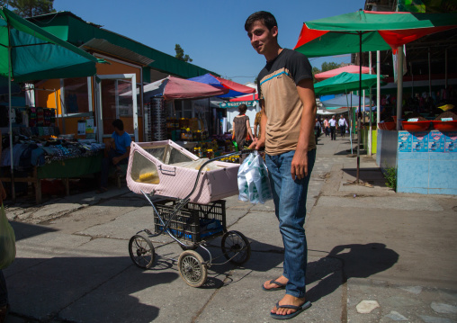 Young tajik man selling corns he has put in a pram on a local market, Gorno-Badakhshan autonomous region, Khorog, Tajikistan