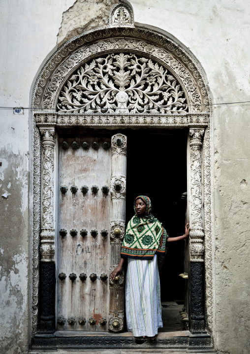 Swahili girl standing in front of  an old door in stone town zanzibar, Tanzania