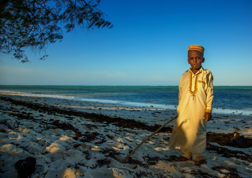 Tanzania, Zanzibar, Kizimkazi, young muslim boy in school uniform on beach