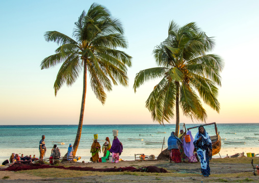 Tanzania, Zanzibar, Kizimkazi, women carrying fishes in a bucket on their heads