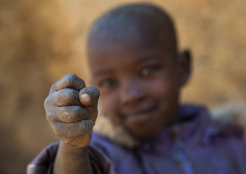 Tanzania, Serengeti Plateau, Lake Eyasi, hadzabe tribe boy showing how to say the number five with the fist