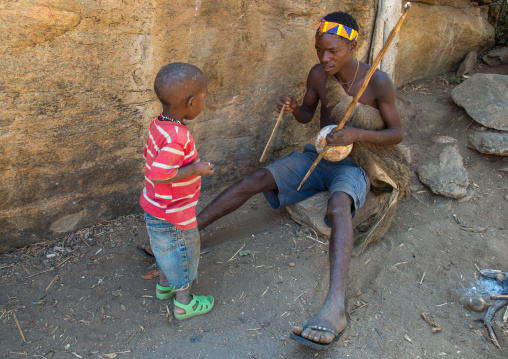 Tanzania, Serengeti Plateau, Lake Eyasi, hadzabe tribe man playing music to his child