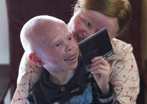 Tanzania, East Africa, Dar es Salaam, mariam staford and baraka cosmas people with albinism looking at a polaroid picture at under the same sun house