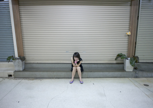 Girl looking at her mobile phone in the street, Bangkok, Thailand