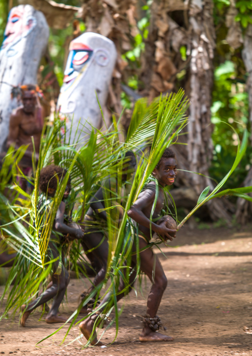 Small Nambas children covered with palm leaves dancing in front of slit gong drums during the palm tree dance, Malekula island, Gortiengser, Vanuatu