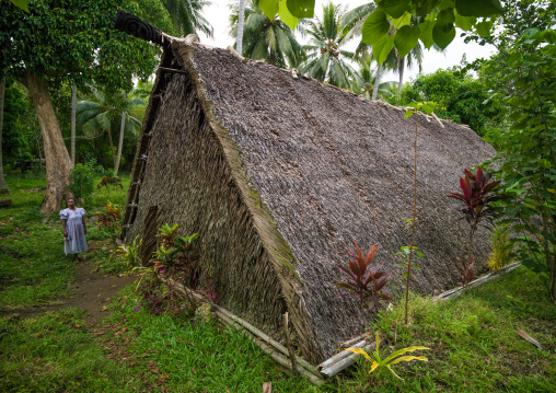 A woman standing in front a traditional meeting place called a nakamal where only men can enter, Malampa Province, Malekula Island, Vanuatu