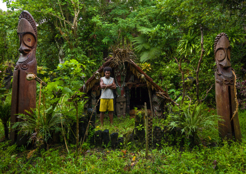 Ni-Vanuatu standing in front of a nakamal with slit gong drums in the jungle, Ambrym island, Olal, Vanuatu