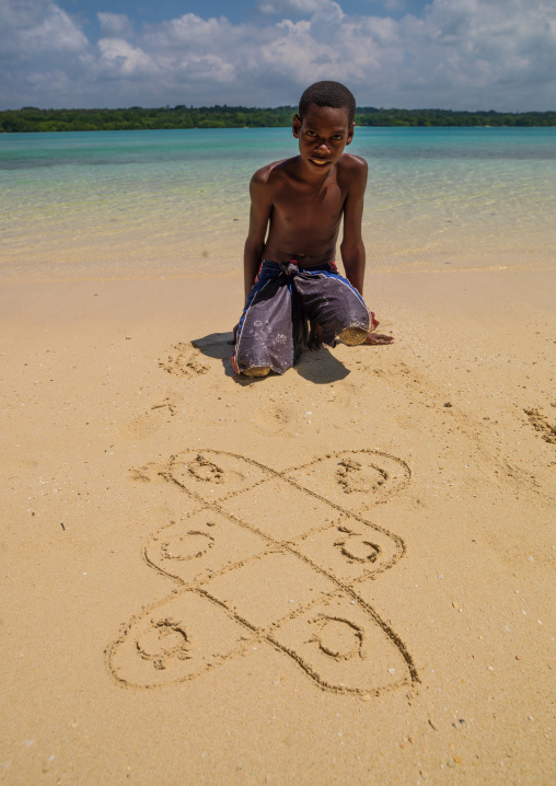 Boy on the beach making a traditional sand drawing, Sanma Province, Espiritu Santo, Vanuatu