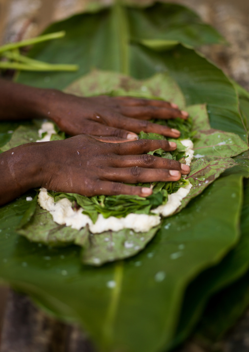 Woman cooking a bougna in a green banana leaf, Tanna island, Epai, Vanuatu