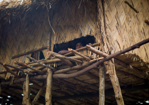 Young man looking thru the window of his traditional house, Tanna island, Yakel, Vanuatu