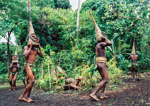 Tribesmen dancing in the jungle with helmet masks for a circumcision ceremony, Malampa province, Malekula island, Vanuatu