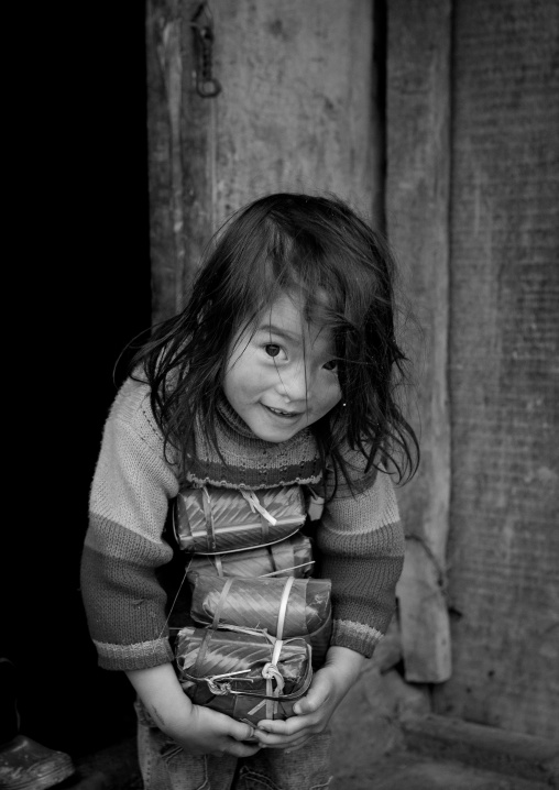 Black hmong girl holding holding wrapped rice cakes for tet, Sapa, Vietnam