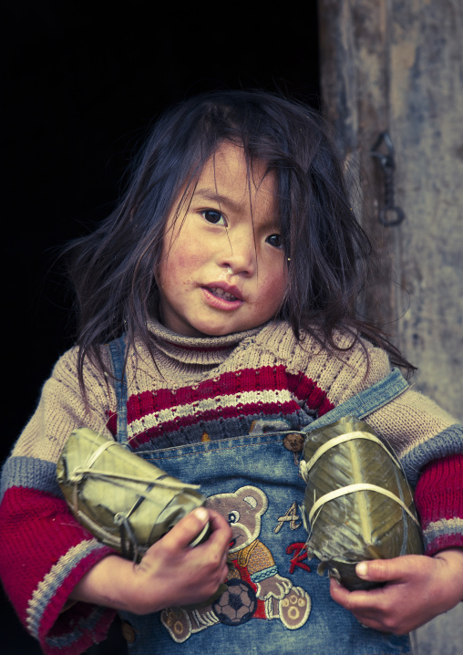 Black hmong girl holding holding wrapped rice cakes for tet, Sapa, Vietnam