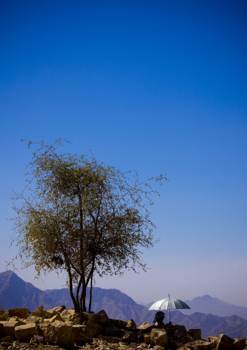 Old Man Sitting Under The Shade Of An Umbrella In The Mountain, Hababa, Yemen