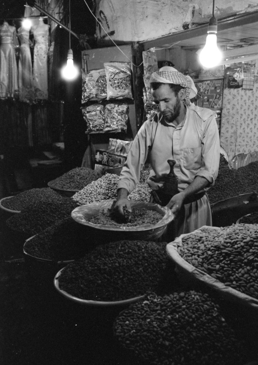 Yemeni Grocer Picking Up Grains In The Souq, Sanaa, Yemen