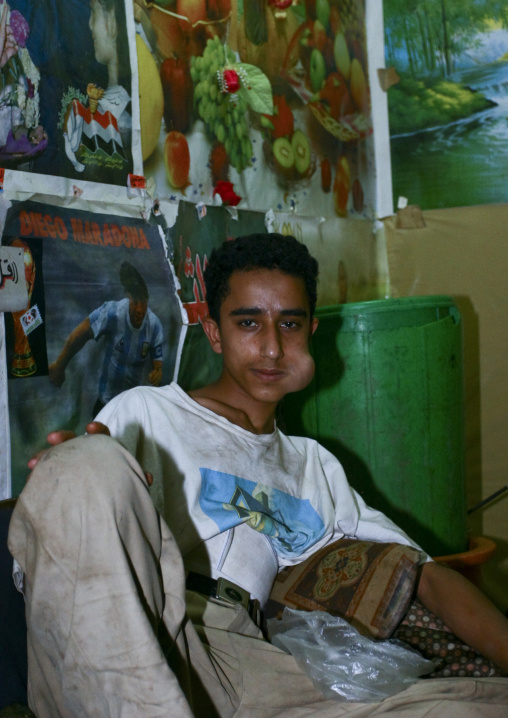 Young Man Lying Down And Chewing Qat In A Room Full Of Posters, Sanaa, Yemen